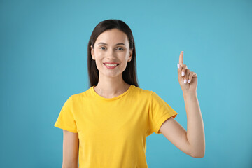 Beautiful woman having idea on light blue background