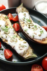 Slices of grilled eggplant with pumpkin seeds, tomatoes and yoghurt on table, closeup