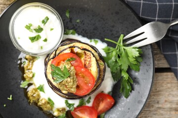 Tasty grilled eggplant slices with tomatoes, pesto and yoghurt on wooden table, top view
