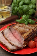 Delicious baked beef meat, tomatoes and basil on table, closeup
