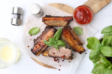 Roasted beef ribs with spices, ketchup and drink on white tiled table, flat lay