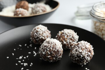 Tasty chocolate candies with coconut flakes on white table, closeup