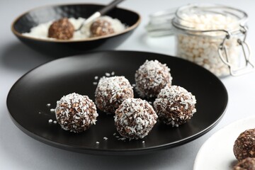 Tasty chocolate candies with coconut flakes on white table, closeup