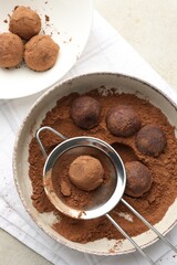 Making tasty chocolate candies with cocoa powder at light table, flat lay