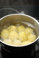 Young potatoes boiling in pot on stove, closeup