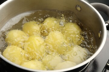 Young potatoes boiling in pot on stove, closeup