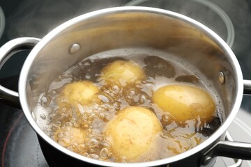 Young potatoes boiling in pot on stove, closeup
