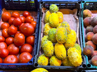 Tomatoes and horned melons neatly arranged in market crates. Agricultural harvest, nutrition, and consumer demand reflected in colorful seasonal produce.