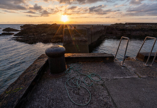Sunrise over harbour wall at St Abbs