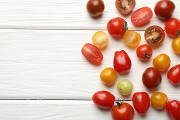 Different ripe tomatoes on white wooden table, flat lay. Space for text