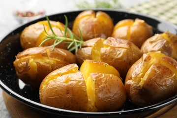 Tasty baked potatoes with rosemary served on table, closeup