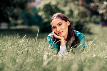 Cute woman in casual attire enjoying a sunny day on the grass, highlighting her carefree lifestyle and youthful energy outdoors