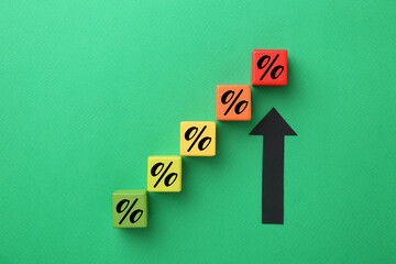 Colorful cubes with percent signs and arrow on green background, top view