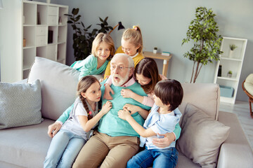 Photo of funky funny smiling cheerful family grandchildren tickling grandfather in glasses enjoying weekend at home house