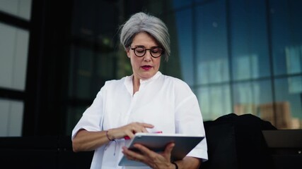 Confident senior woman holding tablet and speaking on smartphone outdoors. Concept of professional communication, leadership, and digital independence in modern career
- Powered by Adobe