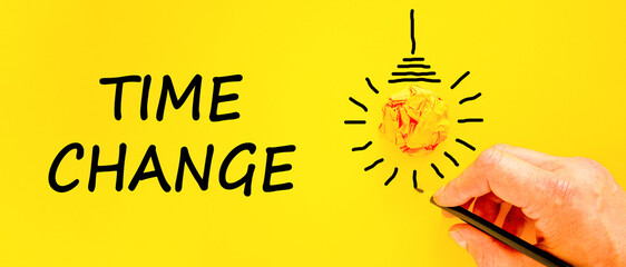 Time change symbol. Concept word Time change on beautiful yellow paper. Businessman's hand. Light bulb icon. Beautiful yellow paper background. Business time change concept. Copy space.