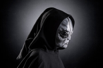 Mysterious humanoid alien at night over dark misty background