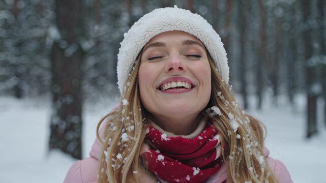 Young woman wearing winter clothes enjoying snowfall in a forest