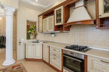 classic kitchen design with beige cabinets, brown accents, a tile backsplash, and stainless steel appliances