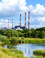 Obraz premium Power plant by river under a cloudy sky