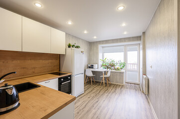 bright, modern kitchen with white cabinets, wood countertops, and a small dining area by the window filled with plants