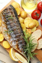 Tasty roasted mackerel with spices and vegetables on table, flat lay. Homemade seafood dish