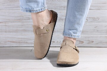 Woman in stylish beige slippers on light wooden floor, closeup