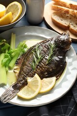 Tasty roasted flounder fish with celery served on blue table, closeup. Homemade seafood dish