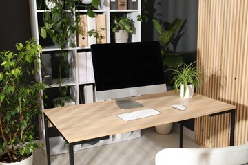 Stylish workplace with modern computer and floral decor in office. Biophilic interior design