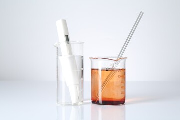 Clean and dirty water in beakers with quality meter on white background
