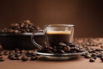 Cup of hot coffee and beans on brown background, closeup