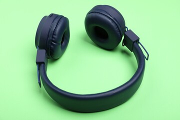 Pair of stylish blue headphones on light green background