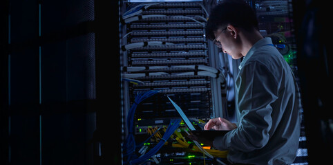 Computer engineer is setting up network in server room,Systems Maintenance Technician,Male engineer working in server room at modern data center