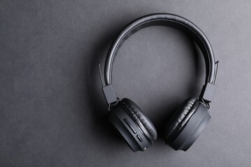 Pair of stylish headphones on black background, top view. Space for text