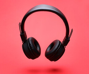 Pair of wireless headphones on coral background