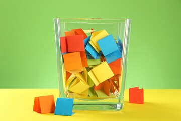 Bright paper pieces in glass jar on color background