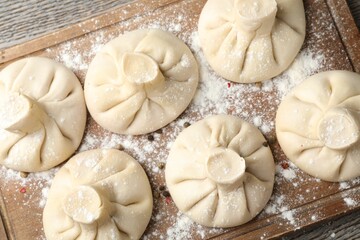 Uncooked khinkalis (dumplings) on wooden table, top view