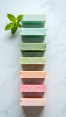 Colorful homemade soaps with mint leaves on a white marble surface for freshness and beauty