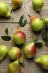Fresh ripe pears and green leaves on wooden table, flat lay