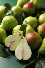 Fresh ripe pears and leaves on green wooden table, closeup