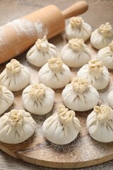 Uncooked khinkalis (dumplings) and rolling pin on table, closeup