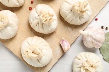 Uncooked khinkalis (dumplings) and spices on white wooden table, flat lay