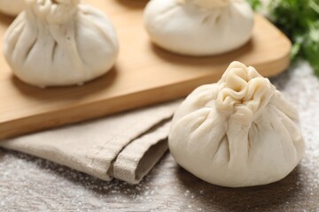 Uncooked khinkalis (dumplings) and cilantro on wooden table, closeup