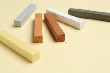 Many colorful chalk pastels on beige background, closeup