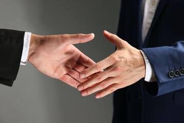 Obraz premium Business partners shaking hands on grey background, closeup