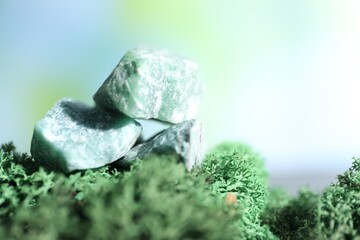 Healing stones on green moss against blurred background, closeup. Space for text