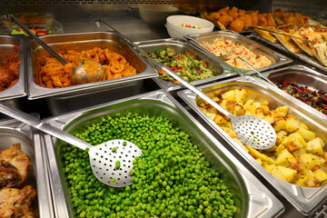 trays of the self service canteen with hot dishes and vegetables like potatoes and green peas