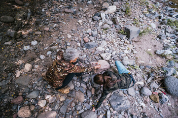 
Mother and daughter having fun making an apacheta next to the river, they smile and enjoy the moment.