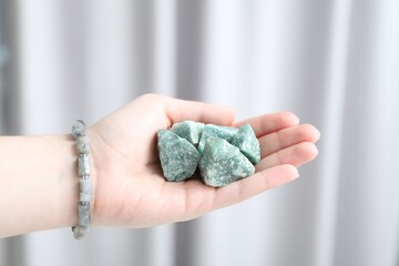 Woman with healing stones on blurred background, closeup