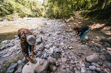 
Mother and daughter having fun making an apacheta next to the river, they smile and enjoy the moment.